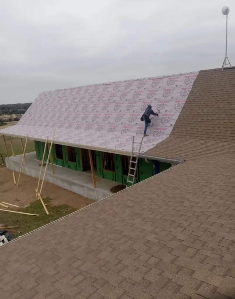 Worker preparing underlayment for a metal roof installation in Springfield